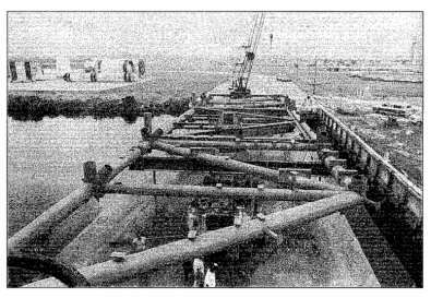 Small-format photograph: The RSS Bottom Truss Weldment, as it sits on top of it's Prime Mover, which is resting on top of the barge which was used to transport it from Sheffield's steel fabrication shop in Palatka, Florida, to the Turn Basin near the VAB at KSC, which is where you see it here, being delivered to the jobsite.